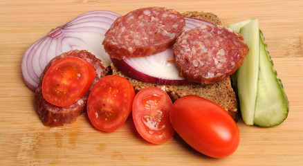 summer sausage , salted cucumber, red cherry tomatoes and sliced red onion Bamboo cutting board , traditional snack while drinking vodka