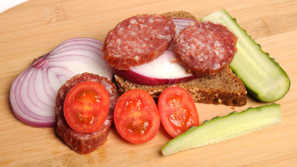 summer sausage , salted cucumber, red cherry tomatoes and sliced red onion Bamboo cutting board , traditional snack while drinking vodka