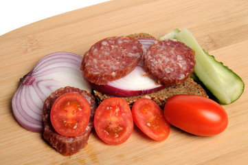 summer sausage , salted cucumber, red cherry tomatoes and sliced red onion Bamboo cutting board , traditional snack while drinking vodka