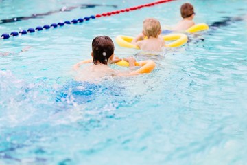 Seven years old boy learning to swim at the pool.