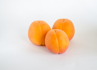 three whole apricots on white background