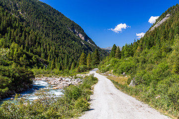 Fototapeta na wymiar Austrian Alps. Starting famous Krimml waterfalls. Crystal clear water sparkles in the midday sun. Through the narrow creek wooden bridge spanned