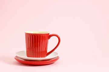 Red coffee cup on white and red plate pastel over pink background.