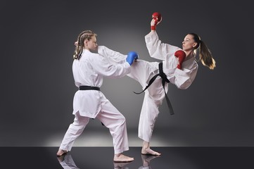 Two female young karate fighting on the gray background