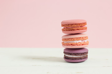 Sweet and colorful french macaroons or macaron on white wooden table pink background, Dessert.