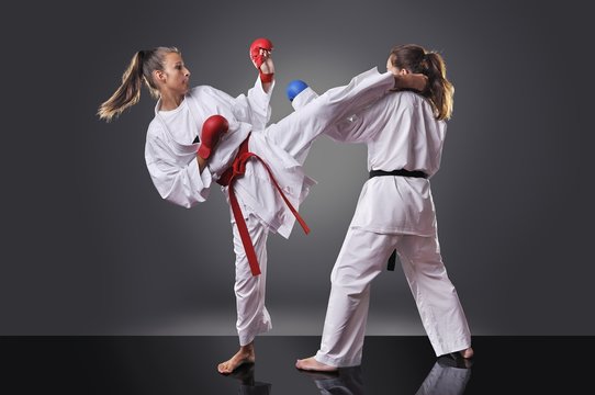Two female young karate fighting on the gray background