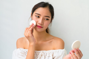 Obraz na płótnie Canvas Young woman applying foundation on face with powder puff,