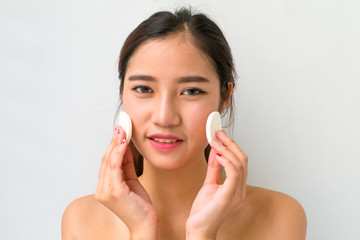 Young woman applying foundation on face with powder puff,