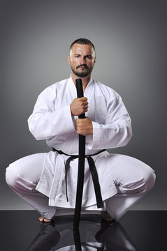 Handsome young black belt male karate posing with sword on the g