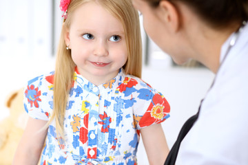 Pediatrician is taking care of baby in hospital. Little girl is being examine by doctor by stethoscope. Health care, insurance and help concept.