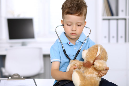 Little doctor examining a .toy bear  patient by stethoscope