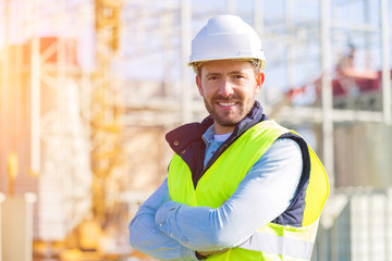 Portrait of an attractive man worker on a construction site - obrazy, fototapety, plakaty