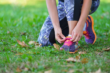 Fototapeta na wymiar Female jogger tying laces on her shoes outside