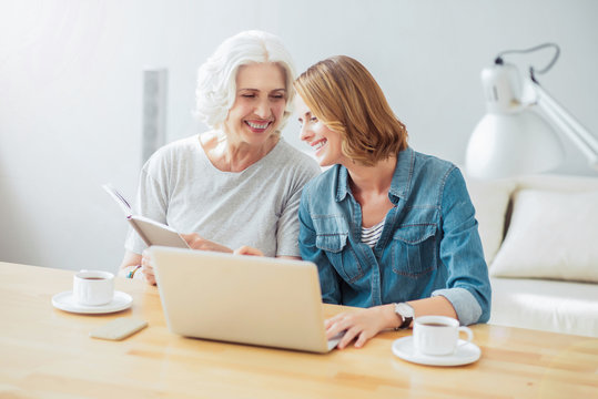 Cheerful mother and her adult daughter resting at home