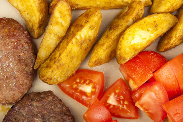 Beef burgers with potato wedges and fresh tomato's