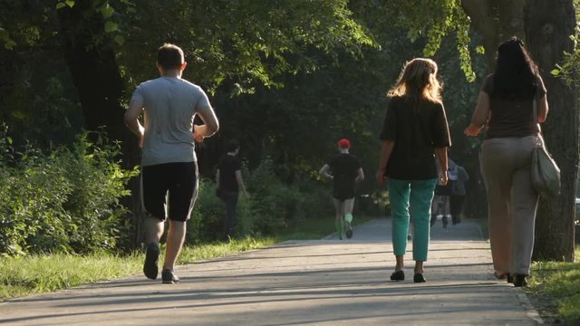 SLOW MOTION: People run and walk in a park
