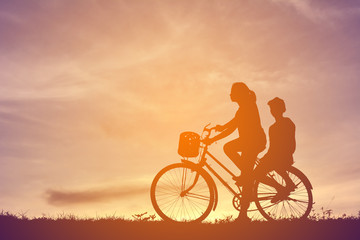 Fototapeta na wymiar Silhouette women and boy with bicycle on sunset