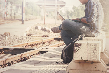The tourist man sitting with a laptop in a train station.Photographed side by customizing vintage...