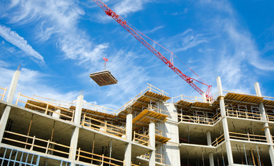 Concrete Highrise Construction site, with tower crane moving materials