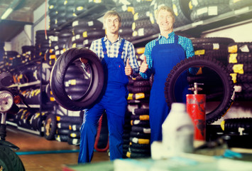 Obraz na płótnie Canvas Two happy colleagues working with motorcycle tires