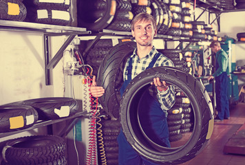 Obraz na płótnie Canvas Glad working man standing with new tires