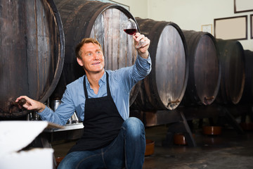 man with glass of wine in wine cellar.