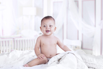 Cute asian baby laughing in the bedroom
