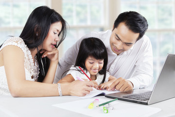 Cute kid doing homework with parents