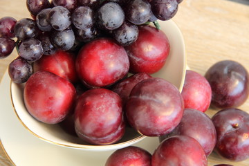 Schale mit Pflaumen und blauen Trauben