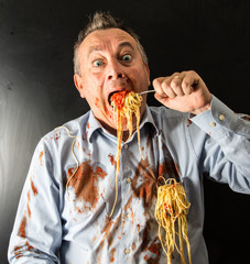 uomo che si ingozza di spaghetti al pomodoro