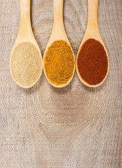 Spice powder on a wooden background. Closeup on paprika, curry and ginger.