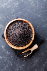 Black rice in wooden bowl on a dark table from above