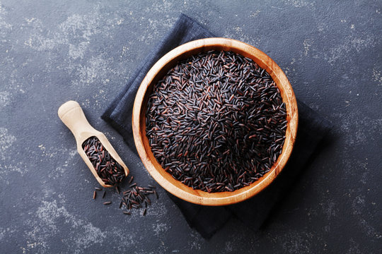 Black rice in wooden bowl on a dark table top view