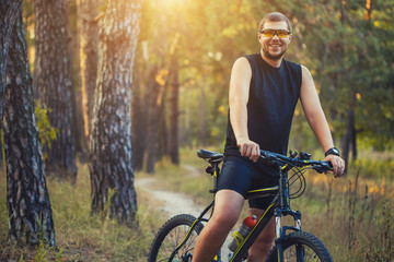 Naklejka premium man cyclist rides forest paths