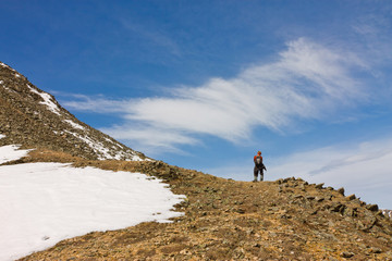 Tourist man with a backpack standing alone in the snow-capped mo