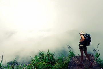 Hikers with backpacks relaxing on top of a mountain and enjoying valley view