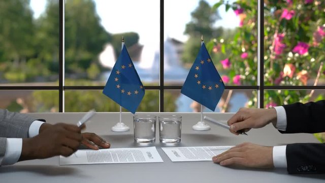 Men are signing papers. Businessmen shake hands at desk. It's time for changes. Leaders of European Union.