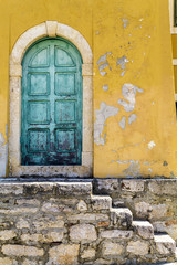 Old rustic green door on a yellow wall
