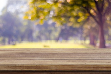 Naklejka na ściany i meble Empty wooden table over blurred tree with bokeh background