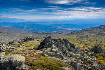 Fototapeta na wymiar Beautiful panoramic image at Vitosha, Sofia, Bulgaria with vast view across several miles - with jagged rocks in the foreground and mountain chains in the foreground