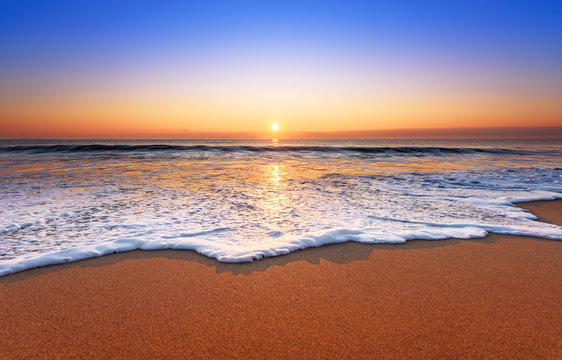 Fototapeta Majestic ocean sunset with a breaking wave.