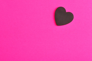 Valentine's Day. A black heart isolated on a pink background
