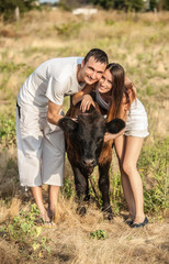young couple of farmers with a bull-calf