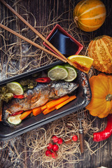 fish on the baking dish with cherry tomatoes, orange, garlic, on