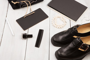 shoes, jeans, notepad and chalkboard on white wooden desk