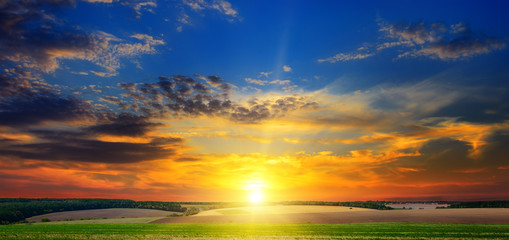 autumn field and evening sunset on the cloudy sky