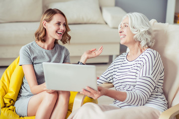Cheerful woman and her grandmother using laptop