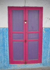 porte rose et violette sur façade blanche et bleue