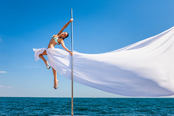 Female pole dancer against the sea and sky