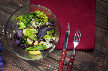 Top view of freshly harvested lettuce, lemon, blue cheese, pearand flowers on an old wood table